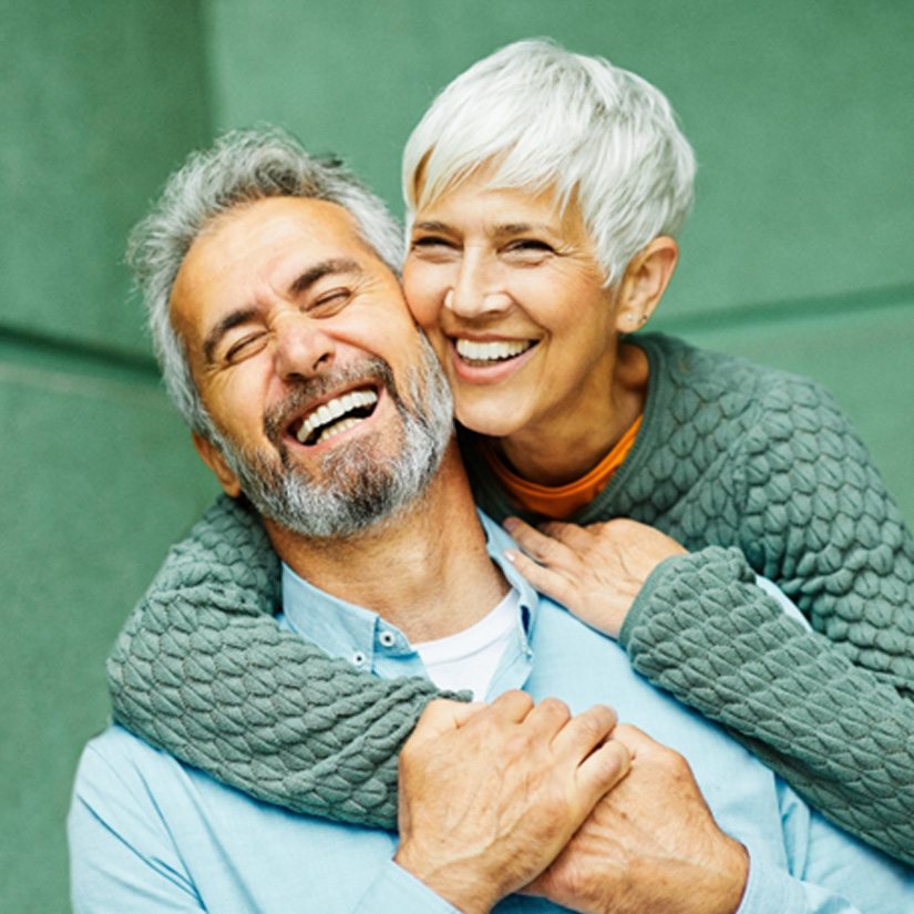 Senior couple standing in front of wall smiling