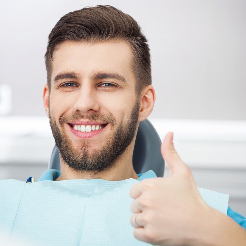 Male patient in dentist’s chair giving thumbs up