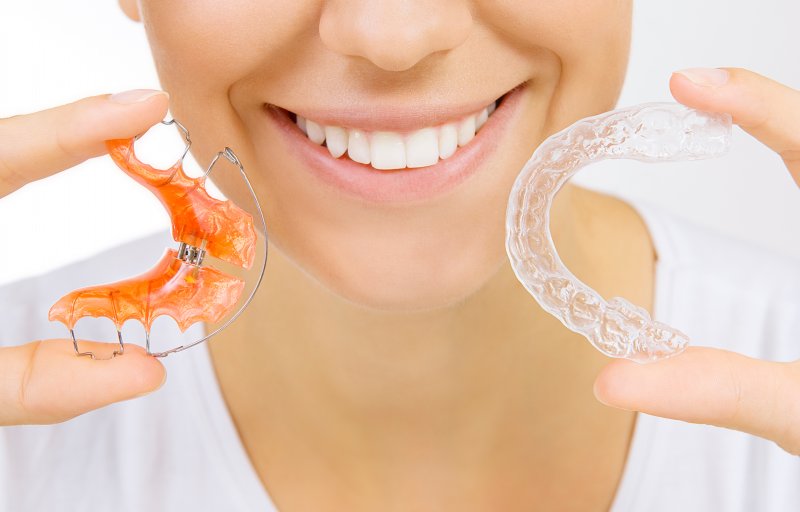 A woman showing off her last Invisalign tray and her retainer